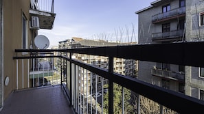 En balkong med utsikt över de intilliggande byggnaderna, en satellantenn och ett metallräcke.