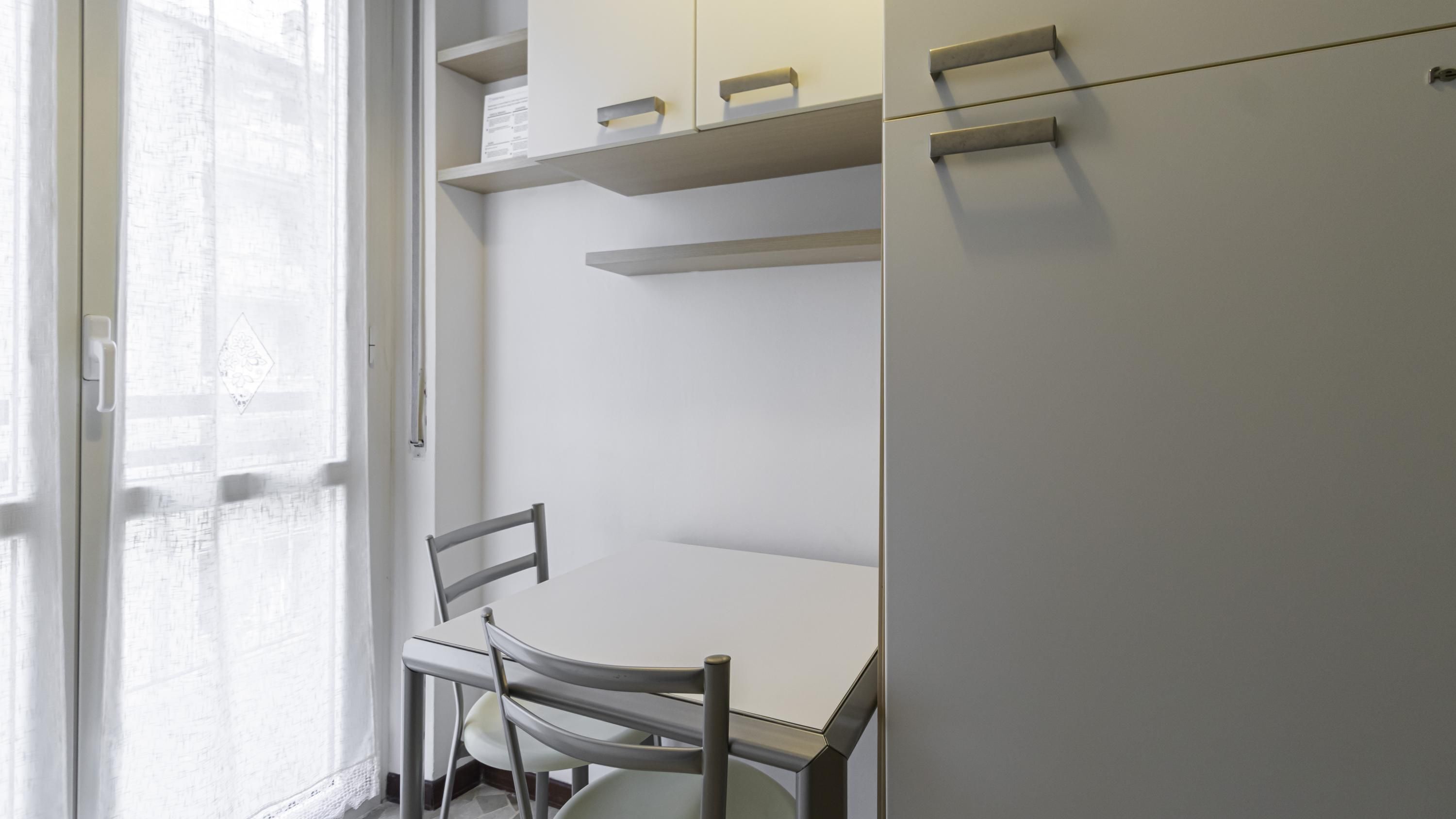 A kitchen with white cabinets, a refrigerator, and a dining table with chairs.