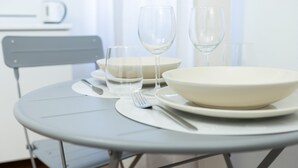 A table set with white plates, bowls, and cutlery, with two empty wine glasses. - Italianway Comfort - Merlo 1 F (Milan)