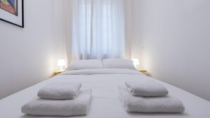 Ein Hotelzimmer mit einem Bett, zwei Nachttischlampen und einem Fenster mit durchscheinenden Vorhängen.
