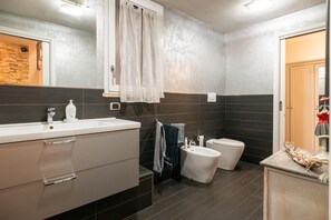 Un baño moderno con un espejo grande, un lavabo, un inodoro y un bidé.