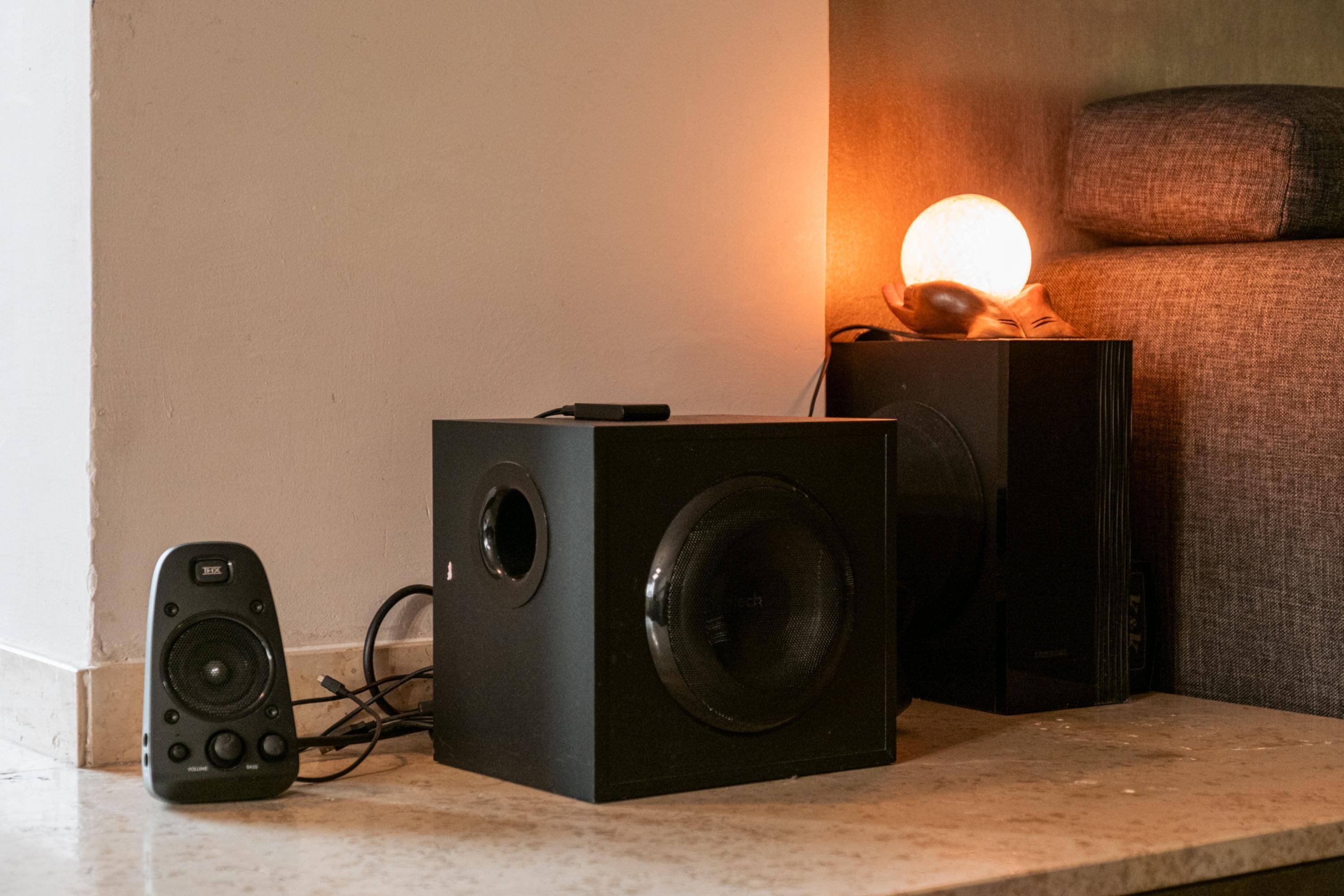 A room with a speaker system and a remote control on a marble surface.