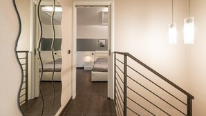 A modern bedroom with a bed, bedside table, and a mirror. - Franciacorta Family Friendly (Adro)