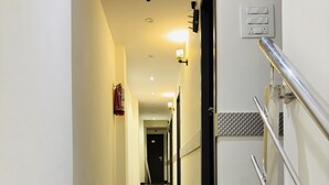 Um corredor de hotel com piso de mármore, corrimão e uma porta no final.