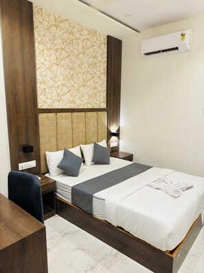 A hotel room with a large bed, a wooden desk, a modern headboard, and a marble-patterned wall. - Hotel Amazing (Mumbai)