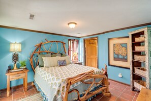 Ein Schlafzimmer mit einem rustikalen Holzbettgestell, einem Nachttisch mit Lampe und einem an der Wand befestigten Regal mit Körben.