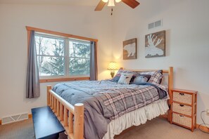 Une chambre à coucher avec un lit en bois, une fenêtre avec des rideaux, une lampe de chevet et des œuvres d’art murales.