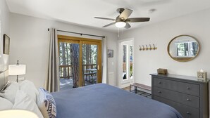 A bedroom with a bed, a dresser, a ceiling fan, a window with curtains, and a door leading to an outdoor area. - Kachina Canyon Overlook Cabin (Kachina Village)