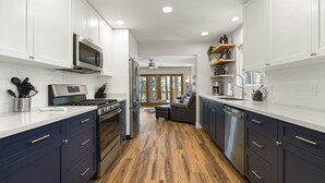 A modern kitchen with white cabinets, a stainless steel range, and a wooden floor. - Kachina Canyon Overlook Cabin (Kachina Village)