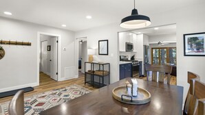 A modern kitchen with white cabinets, a microwave, and a stove. There is a dining area with a wooden table and chairs. - Kachina Canyon Overlook Cabin (Kachina Village)