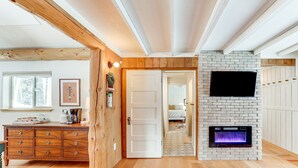 Una habitación amplia con un aparador de madera, una chimenea y una puerta que da a otra estancia.