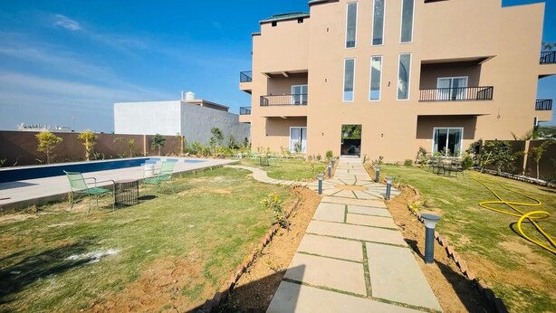 Un immeuble d’appartements moderne doté d’une piscine, d’une pelouse bien entretenue et d’un chemin menant à l’entrée.