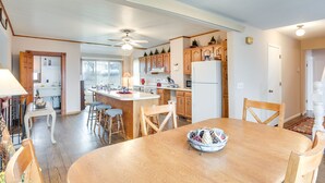 Una cocina amplia con armarios de madera, una isla central y una zona de comedor con una mesa y sillas de madera.