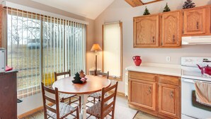 Una cocina con armarios de madera, una estufa blanca y una zona de comedor con mesa y sillas.
