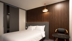 Un dormitorio moderno con una cama, una mesita redonda y una silla.