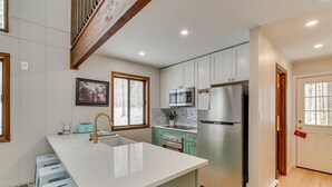 A modern kitchen with a large island, stainless steel appliances, and light-colored cabinetry. - Family-Friendly Big Bass Lake Vacation Rental! (Covington Township)