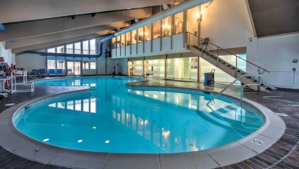 An indoor swimming pool with a central island, a staircase, and a view of the upper floor. - Family-Friendly Big Bass Lake Vacation Rental! (Covington Township)