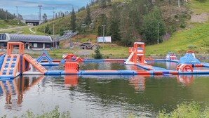 An outdoor water play area with inflatable structures, a small building, and a hill with a ski lift in the background. - Hillaniitty by Interhome (Kuusamo)