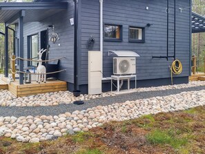 A modern house with a covered porch, a stone pathway, and a large air conditioning unit.