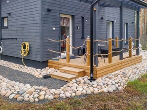 A modern building with a wooden deck, a rope barrier, and a gravel pathway.