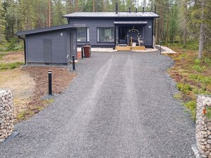 A two-story building with a gravel driveway leading to a wooden deck.