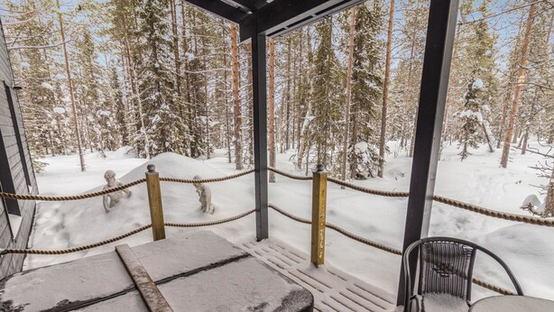 A covered outdoor seating area with a view of a snowy forest. - Hillaniitty by Interhome (Kuusamo)
