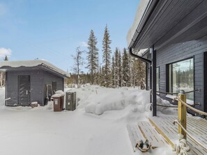 Un área exterior cubierta de nieve con un edificio de madera, un cobertizo pequeño y una pala de nieve.