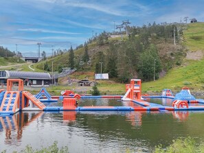 An outdoor water park with inflatable play structures, a ski lift in the background, and a hilly landscape. - Hillaniitty by Interhome (Kuusamo)