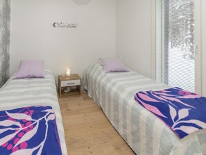 A bedroom with two single beds, a bedside table with a lamp, and a wall sign.