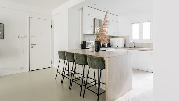 Et moderne køkken med en central ø, barstole og en dekorativ plante.