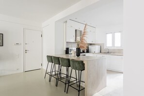 A modern kitchen with a central island, bar stools, and a decorative plant. - Contemporary Bliss 2BR Apartment in Athens (Athina)