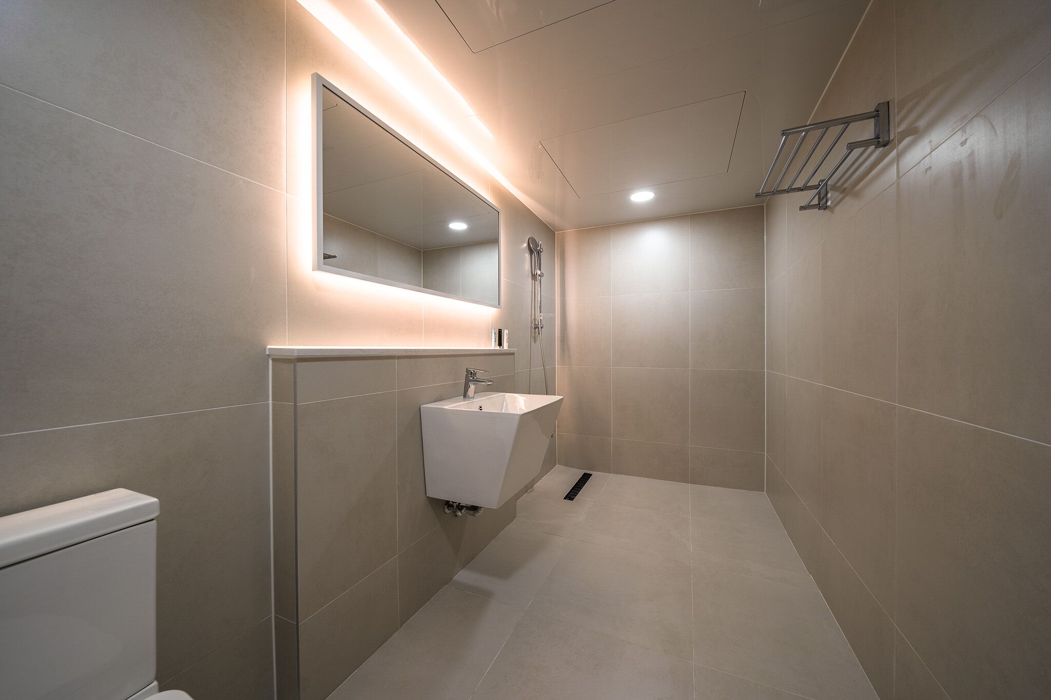 A modern bathroom with a built-in sink, a mirror, and a shower area.