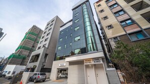 A modern hotel building with a parking garage and a sign for 'MONO HOTEL'. - Mono Hotel (Suwon)