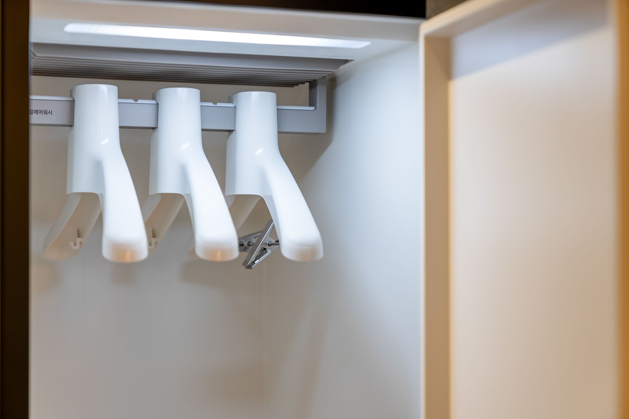 A ceiling-mounted light fixture with three white, curved, elongated arms.