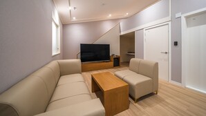 A modern living room with a sofa, coffee table, and TV. - Mono Hotel (Suwon)