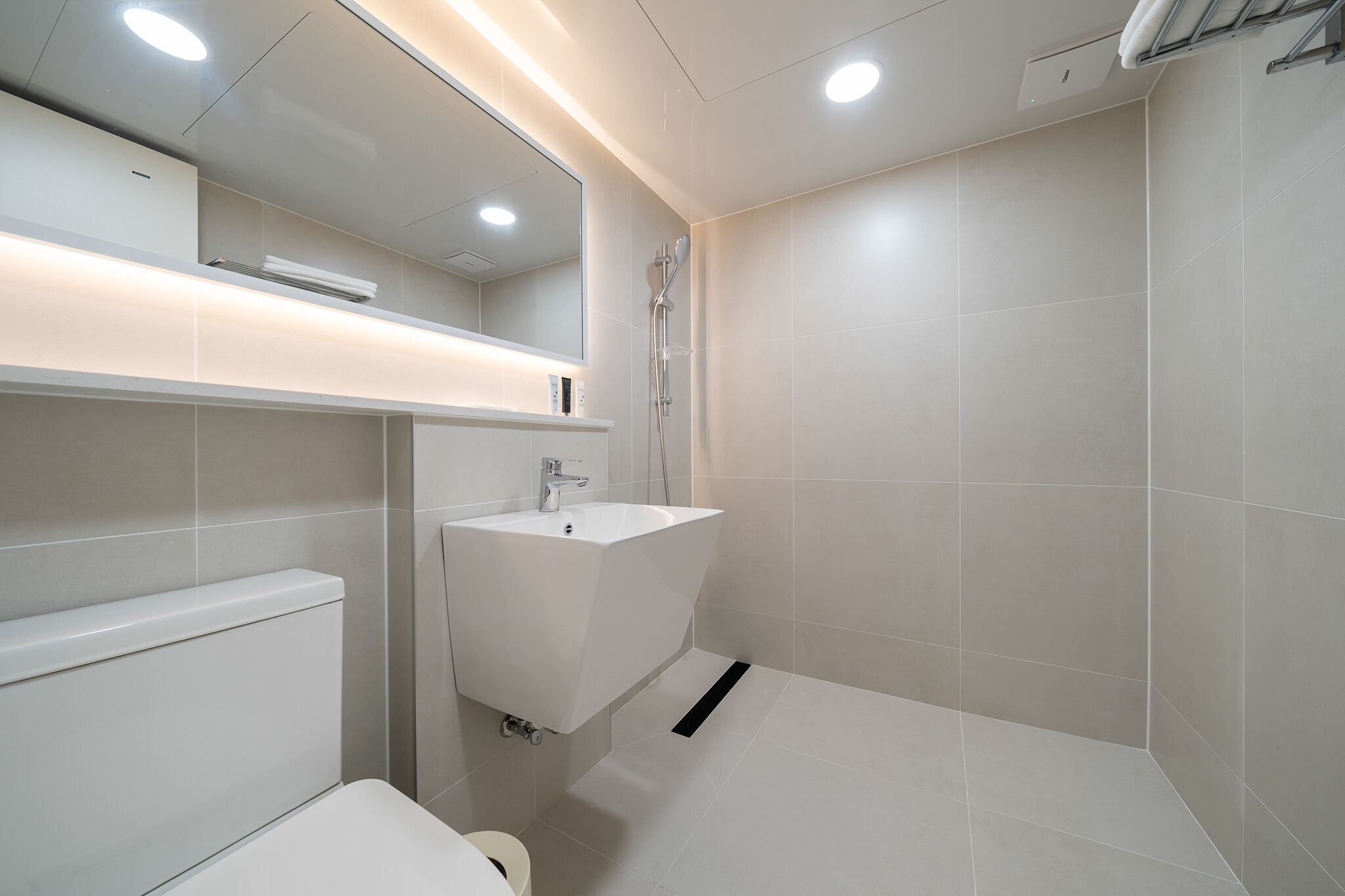A modern bathroom with a white sink, mirror, and shower.