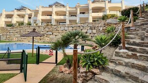 Un hotel con varios balcones, piscina y un muro de contención de piedra.
