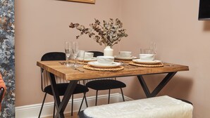 Une table à manger dressée avec des assiettes, des bols et des verres, et un vase rempli de fleurs séchées placé au centre.