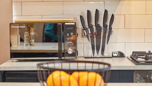 Une cuisine équipée d’un four à micro-ondes, d’un bloc à couteaux et d’un panier à fruits.
