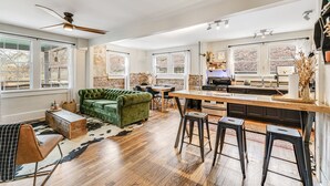 Eine geräumige Küche mit Barbereich, einem grünen Sofa und einem Esstisch.