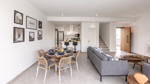 A modern living space with a dining area, a sofa, and a kitchen in the background. - Protaras By the Bay Villa 32 (Paralimni)