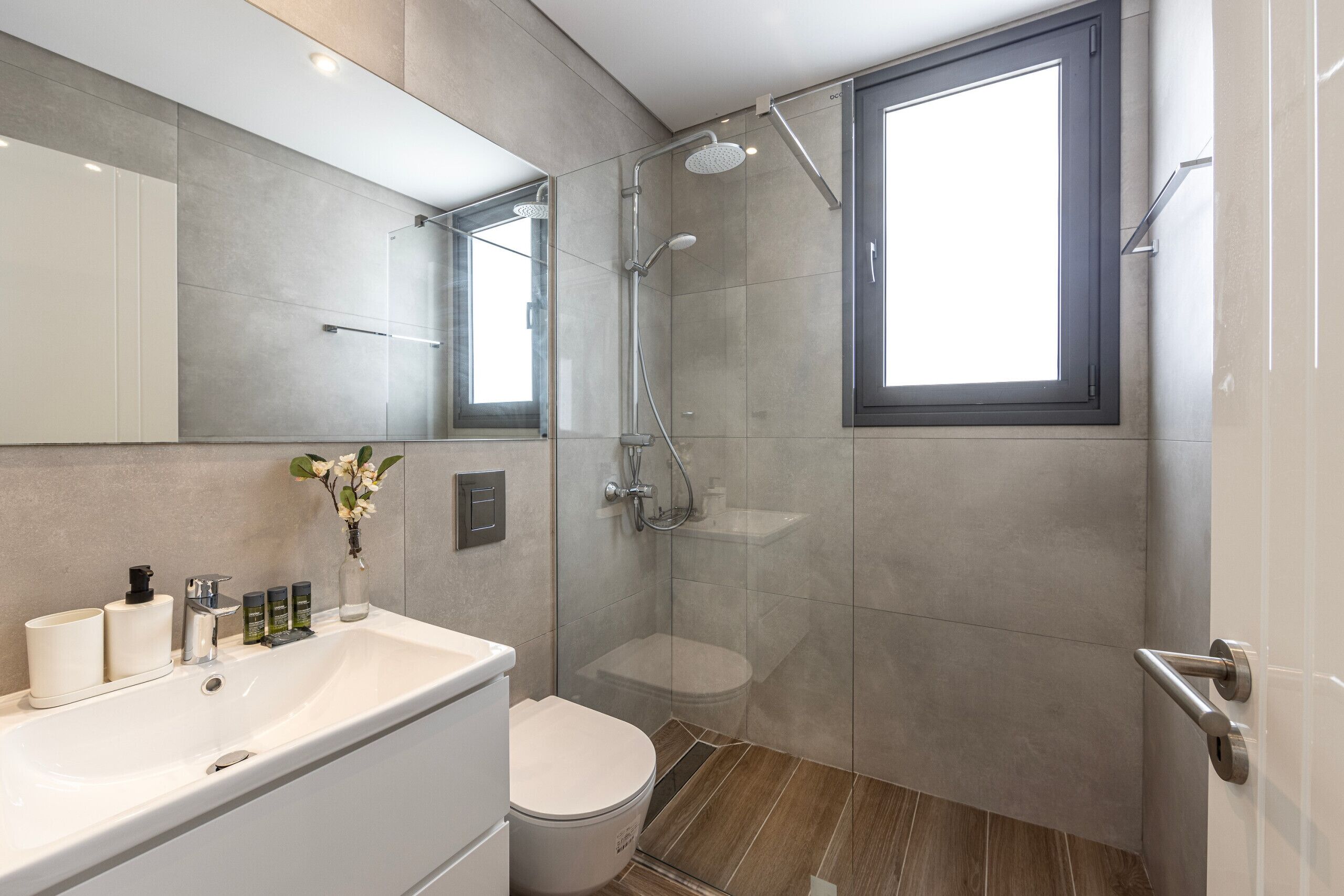 A modern bathroom with a shower, toilet, and sink.