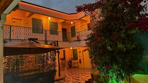 A two-story building with a balcony, outdoor seating area, and a stone wall. - Lotus City Siğacık Boutique Otel  (Seferihisar)