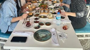 A long dining table with various dishes and drinks, surrounded by people seated on chairs. - Lotus City Siğacık Boutique Otel (Seferihisar)