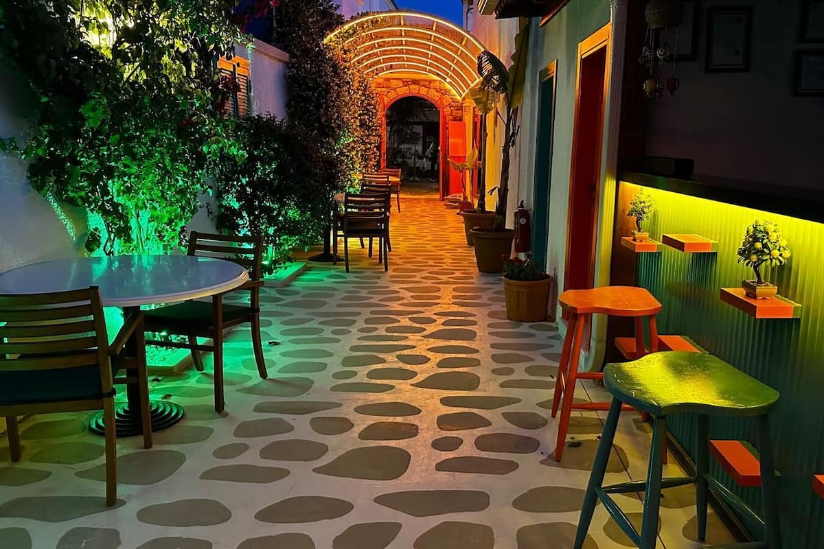 A cozy outdoor seating area with a stone-tiled floor, wooden furniture, and vibrant lighting.