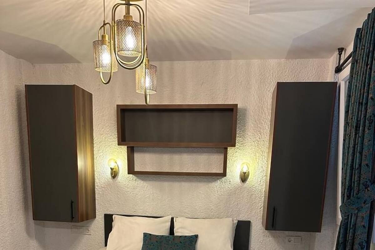 A hotel room with a bed, a nightstand, a wall-mounted TV, and a patterned floor.