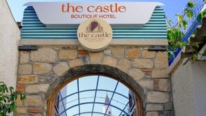 An archway leading to a courtyard with a sign for 'The Castle Boutique Hotel'. - Lotus City Siğacık Boutique Otel (Seferihisar)
