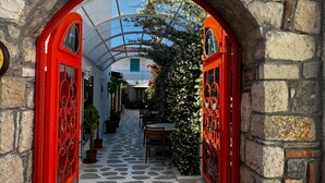 A narrow alleyway with red doors, potted plants, and a stone wall. - Lotus City Siğacık Boutique Otel (Seferihisar)