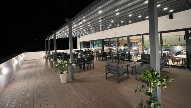 An outdoor patio area with tables and chairs, a covered seating area, and potted plants. - AQUAREL health & spa center (Zalau)