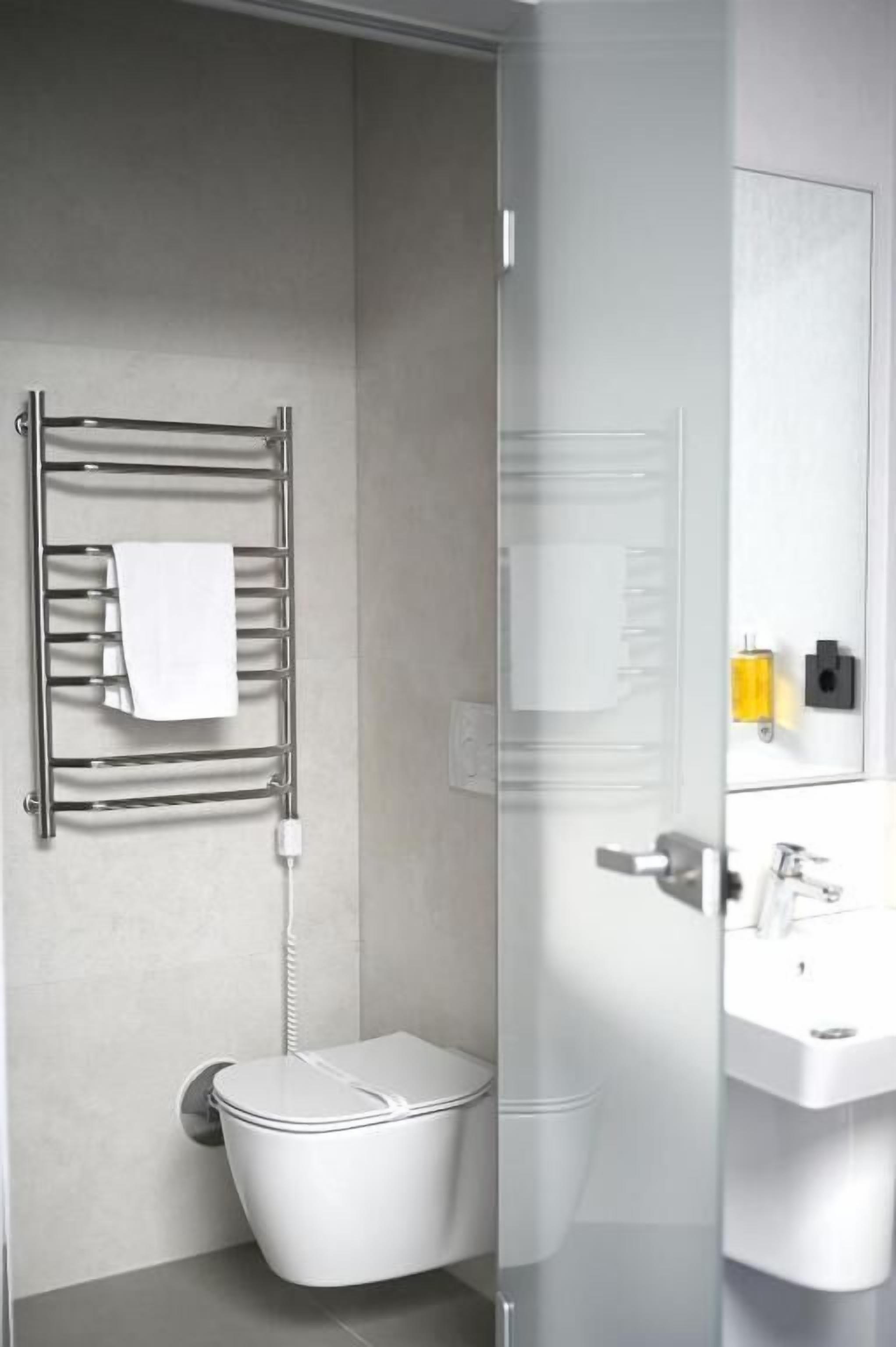 A modern bathroom with a toilet, a towel rack, and a glass shower enclosure.